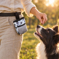 Owner rewarding a border collie from a waist treat pouch during park training